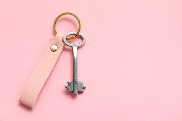 Metal key with leather keychain on pink background