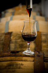 Beer aging in wooden casks is sampled by the brewmaster with a thief and glass