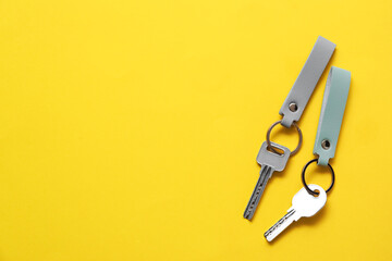 Keys with leather keychains on yellow background