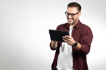 Casual dressed business man using tablet computer, acting worried and looking on tablet. Studio...