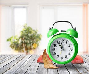 Retro alarm clock and autumn leaves on the desk