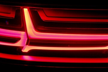 Close up of Red rear light of luxury SUV / Dark neon bright red light of a car background image....