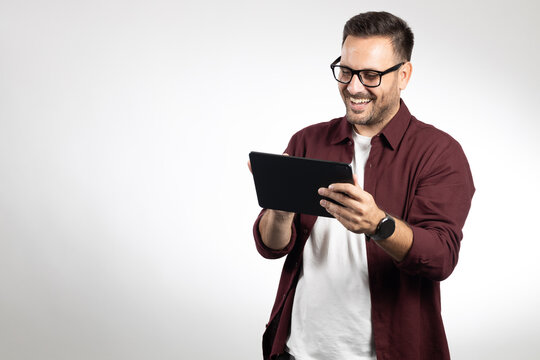 Casual dressed business man using tablet computer, acting worried and looking on tablet. Studio portrait, picture on white background