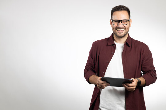 Casual dressed business man using tablet computer, acting worried and looking on tablet. Studio portrait, picture on white background
