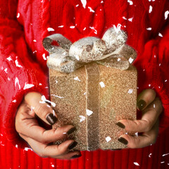 A woman holding gold gift sparkling box