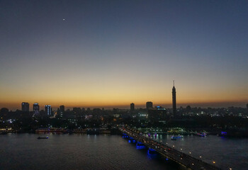 Fototapeta na wymiar Cairo, Egypt: Cairo Tower and the Qasr el Nile Bridge at sunset. On Gezira Island in the River Nile, the tower is the tallest structure in Egypt.