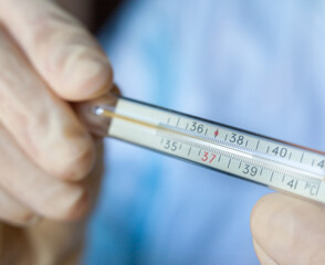 Hands holding medical thermometer.