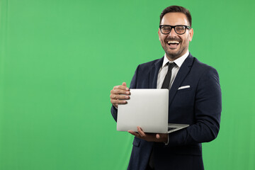 Studio portrait of business man using and holding laptop. Portrait taken on green screen, suitable for editing. Green background