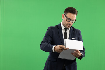Picutre of a young business man, formal dressed in suit, taking notes and showing emotions while doing it. Studio portrait od green background, suitable for editing
Green screen photo background