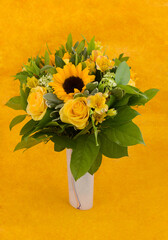Yellow mixed flowers bouquet on yellow background.