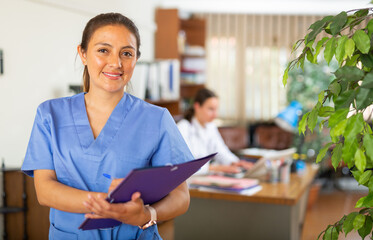 Portrait of confident smiling woman medical worker standing in clinic office