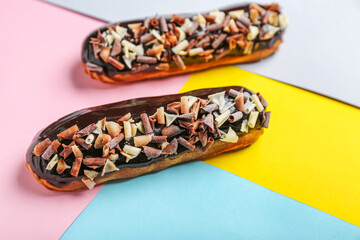 Delicious chocolate eclairs on color background, closeup