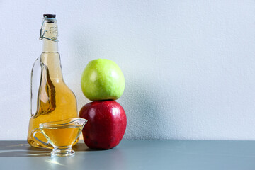 Bottle and gravy boat of apple cider vinegar on table