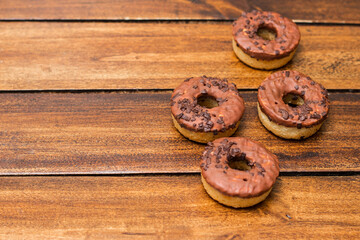 Chocolates covered donuts on wooden background