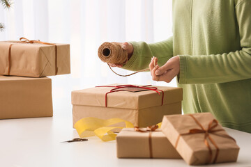 Fototapeta na wymiar Woman with rope and Christmas gift box at table, closeup