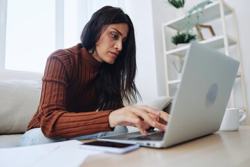 A woman does financial calculations and document analysis at home with a laptop, a freelancer works over the Internet in a home office