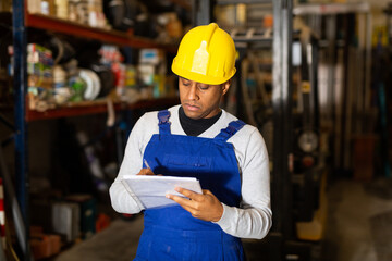 Confident hispanic worker taking inventory of goods in building materials store