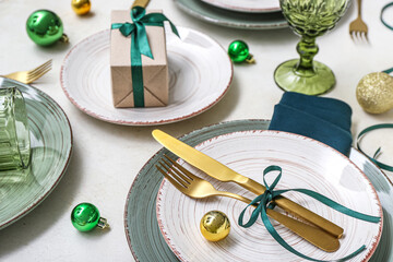 Beautiful table setting with Christmas balls and gift on white background, closeup