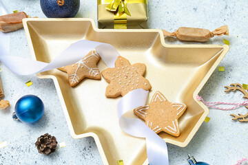 Fototapeta premium Plate in shape of Christmas tree with treats, decor and gift on grunge background, closeup