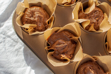 Freshly made chocolate cupcake dough in a white cotton-based baking dish