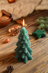 Burning Christmas tree candle on wooden table, closeup