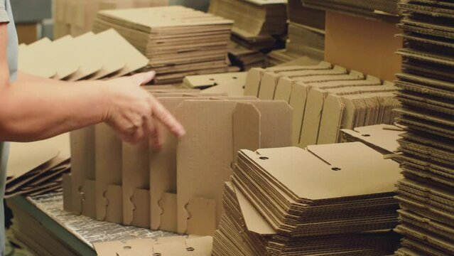 A worker at a cardboard box factory assembles packaging from harvested parts.