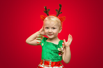 A funny little girl with Klaus deer roses on a red background. Christmas Day. New Year's photophone.