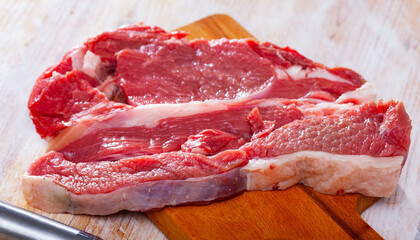 Fresh raw beef steak on wooden background with herbs