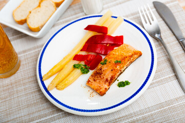 Deliciously steak of fried salmon with asparagus, pepper and herbs on a ceramic plate