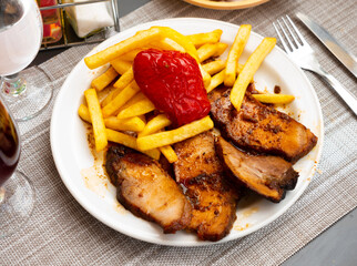 Slices of juicy roasted pork tenderloin served with vegetable garnish of French fries and baked red pepper..