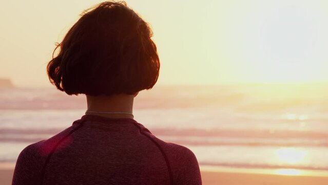 Woman sitting at lotus pose and practicing yoga outdoors