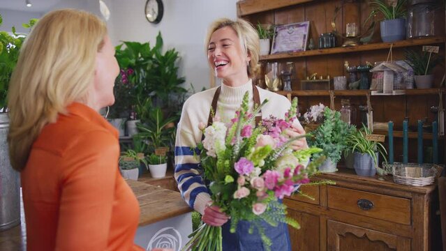 Mature woman buying bouquet of flowers in florists shop - shot in slow motion