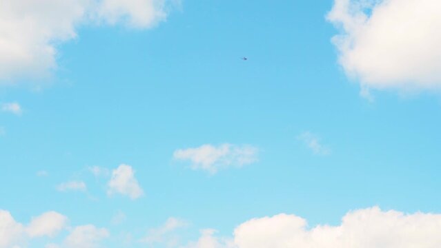 Tiny white private helicopter flies along boundless blue sky on warm sunny summer day. Concept sky transport