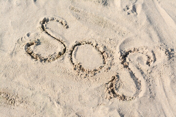 SOS message written on sandy beach outdoors