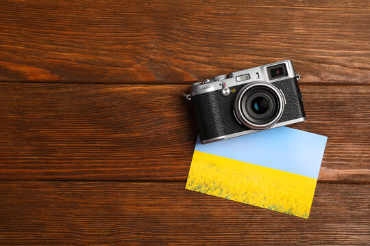 Vintage photo camera and beautiful printed picture on wooden table, flat lay with space for text. Creative hobby