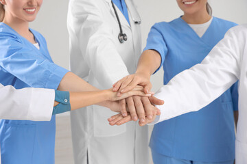 Team of medical doctors putting hands together indoors, closeup