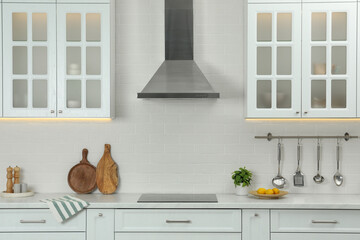 Elegant kitchen interior with modern range hood over cooktop and stylish furniture