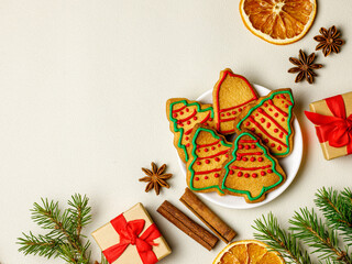 Christmas corner border. Gingerbread cookies on plate, spices, christmas tree branches and decorations on white wooden background. Top view, flat lay, Xmas greeting card with copy space