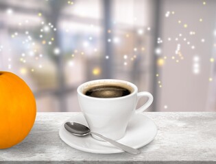 Hot cup with drink, fresh pumpkins on the desk