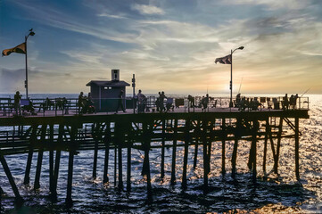 Sunset silhouette of people fishing on the Pier