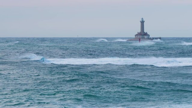 Lighthouse Porer on stormy weather, big waves making crests, grebes flying through restless sea