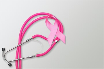 Pink silk ribbon with medical stethoscope on desk