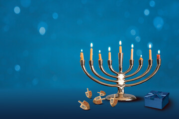 Traditional Chanukah Menorah with dreidels and gift box on blue background