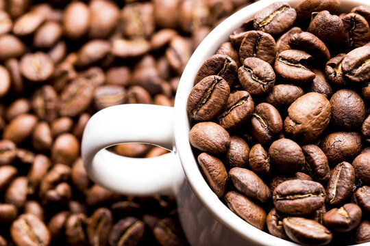 Roasted coffee beans in a cup, on dark background, close-up image, space for text