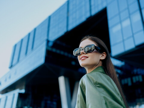 Portrait of a woman against the glass business buildings in the city wearing black fashion sunglasses