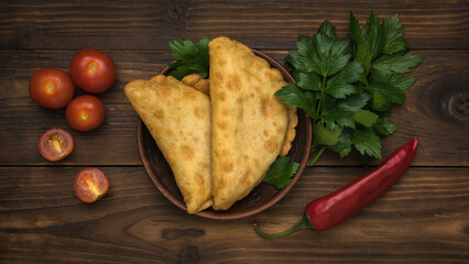 Two fresh pies with meat and herbs on a dark wooden table.