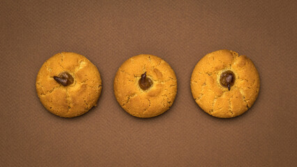 Three fresh round cookies on a brown background.