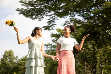 Diversity of gay couple having fun together walking outside in the park. Young women having a date...