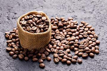 Roasted coffee beans in a cloth sack, on a dark background, close-up image, space for text