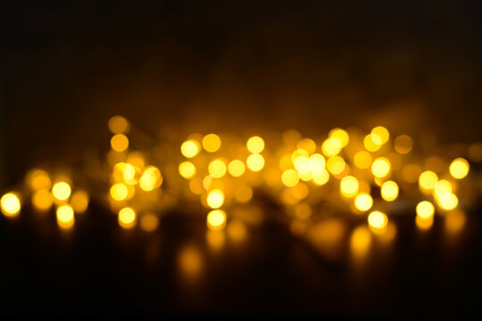 Golden bokeh on a black background, unfocused Christmas lights. Festive, New Year, Christmas background with blurred lights